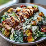 Chopped romaine and creamy Caesar dressing in a Romaine Caesar Bowl, with grilled chicken on the side.