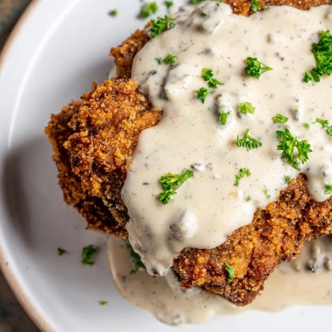 Crispy, golden Chicken Fried Steak with rich, creamy gravy, ready to devour on a plate.