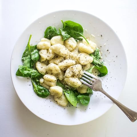 A comforting skillet of Creamy Garlic Gnocchi with golden-brown edges, fresh spinach, and grated Parmesan, ideal for an easy vegetarian dinner.  