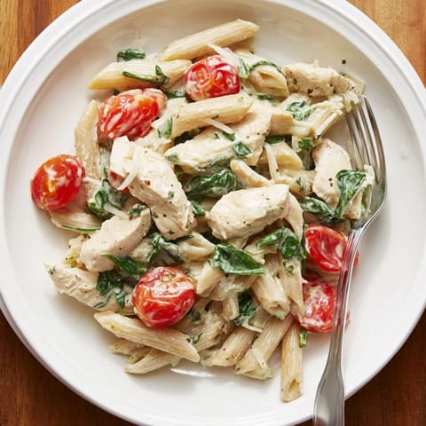 A close-up of a steaming bowl of Greek Yogurt Chicken Pasta, featuring golden chicken, al dente pasta, and a rich yogurt sauce garnished with fresh basil and Parmesan.