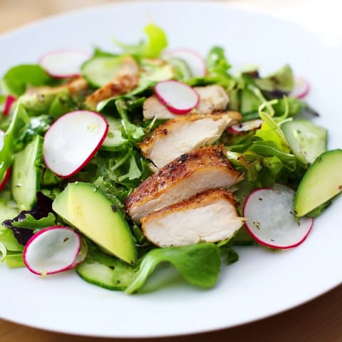 Freshly grilled chicken slices rest on a vibrant bed of mixed greens, cucumber, and radish in this Spring Detox Chicken Salad, dressed in a glistening lemon vinaigrette.