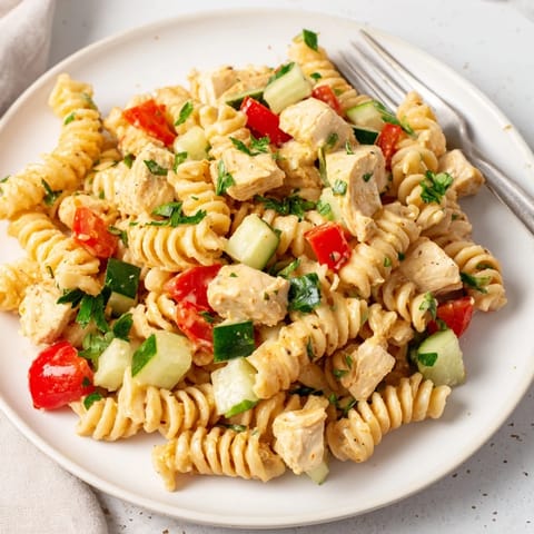 Freshly tossed Honey Mustard Chicken Pasta Salad with spiral pasta, diced chicken, red bell pepper, celery, and parsley garnish, perfect for a light lunch or picnic spread.
