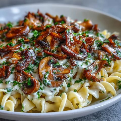 Luscious umami Creamy Mushroom Stroganoff coated in silky sauce, paired with a glass of crisp white wine.