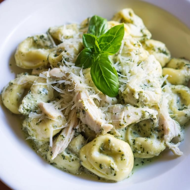 Golden Creamy Pesto Tortellini Skillet garnished with cherry tomatoes and basil, served hot with a fork twirling pasta.  