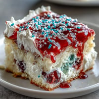 Festive Memorial Day Red White Blue Poke Cake with whipped topping swirls.